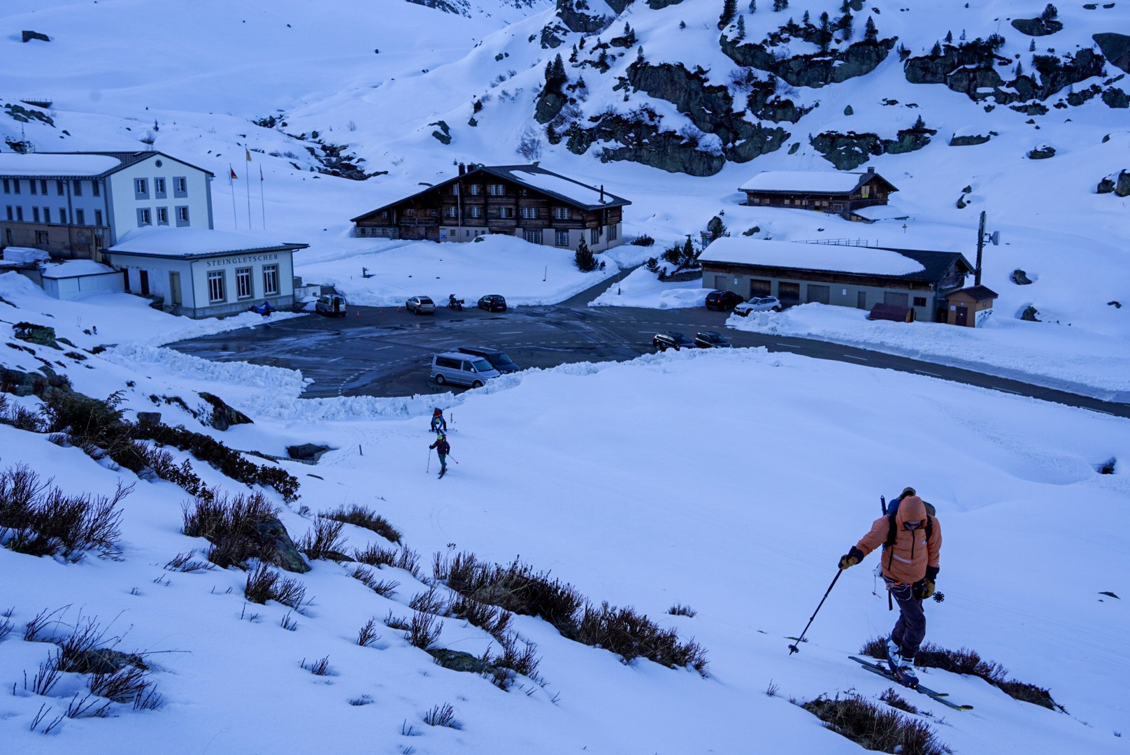 Bâtiments de montagne enneigés au départ de la journée, un skieur au premier plan