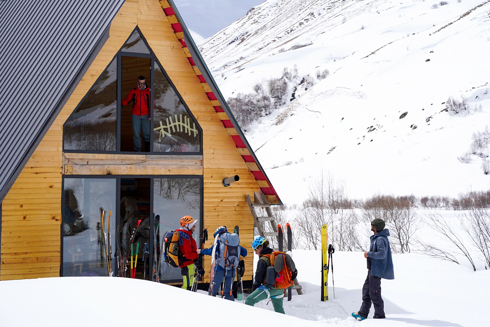 Groupe préparant les skis devant le bâtiment, secteur d’Ushguli et du Shkhara, pendant une traversée à ski en Haute-Svanétie.