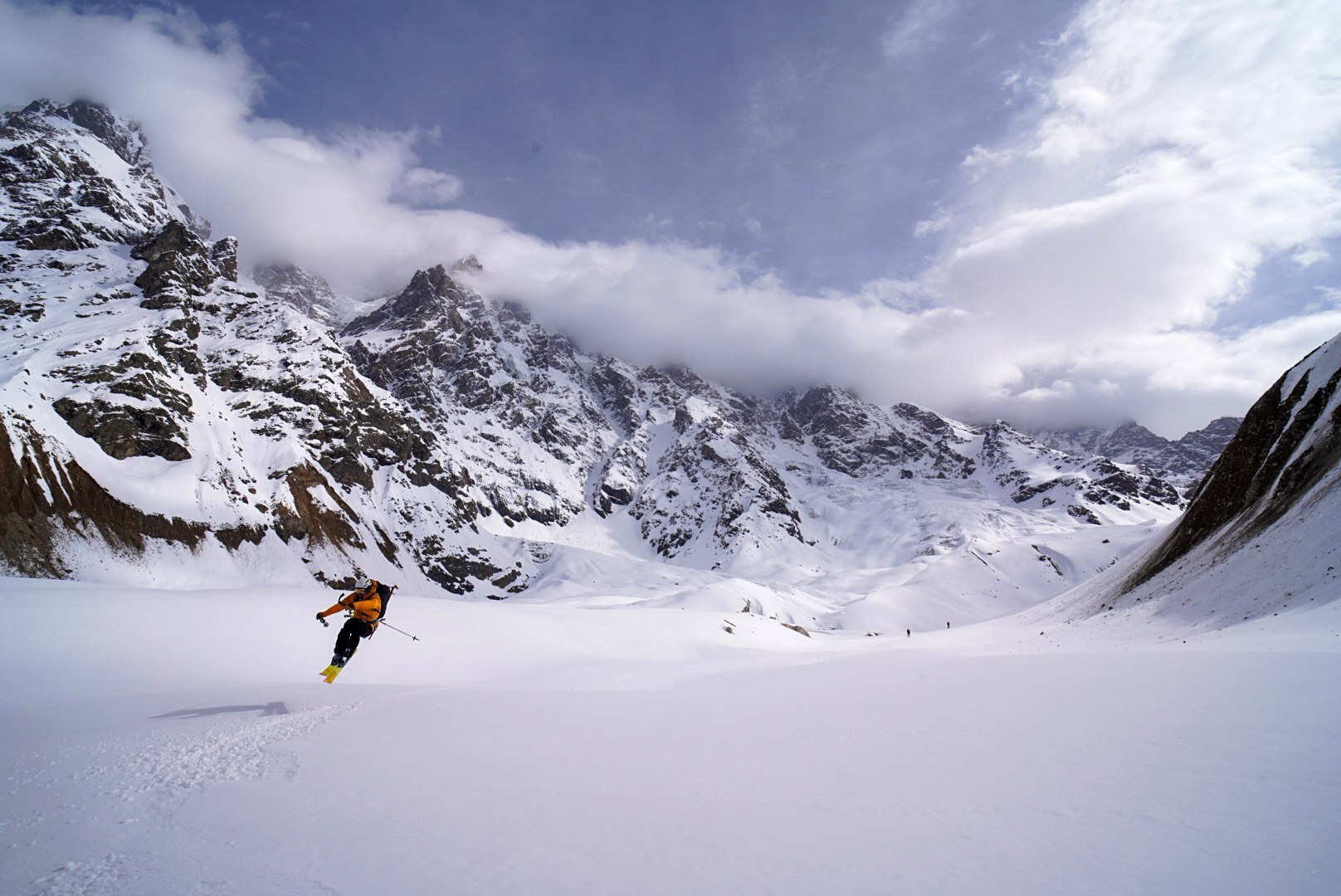 Skieur descendant entre de hauts versants enneigés, secteur d’Ushguli et du Shkhara, pendant une traversée à ski en Haute-Svanétie.