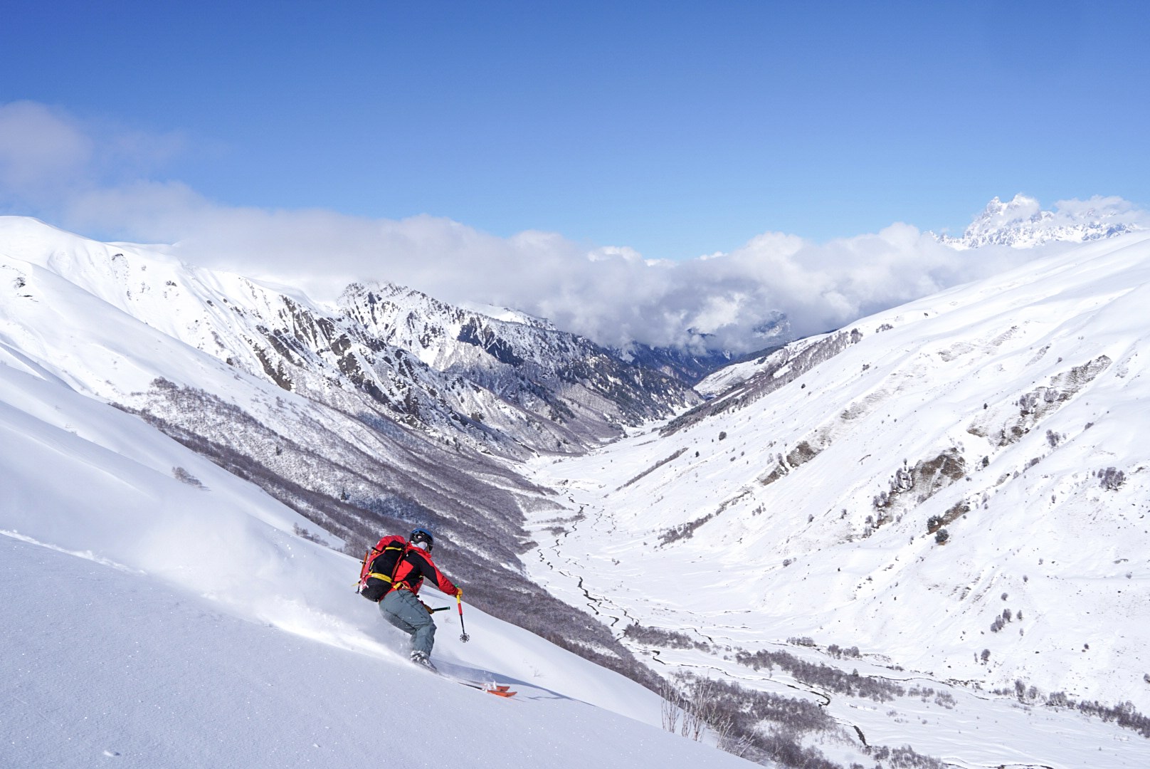 Skieur descendant une grande pente poudreuse, secteur d’Adishi et du Tetnuldi, pendant une traversée à ski en Haute-Svanétie.