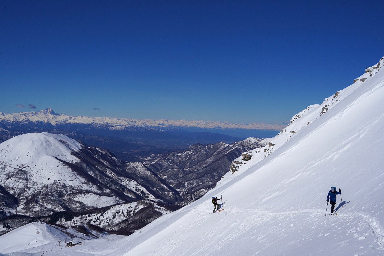Deux skieurs progressant au-dessus d’une vallée du caucase, vallée de Becho, vers le massif de l’Ushba, pendant le voyage à ski en Géorgie.