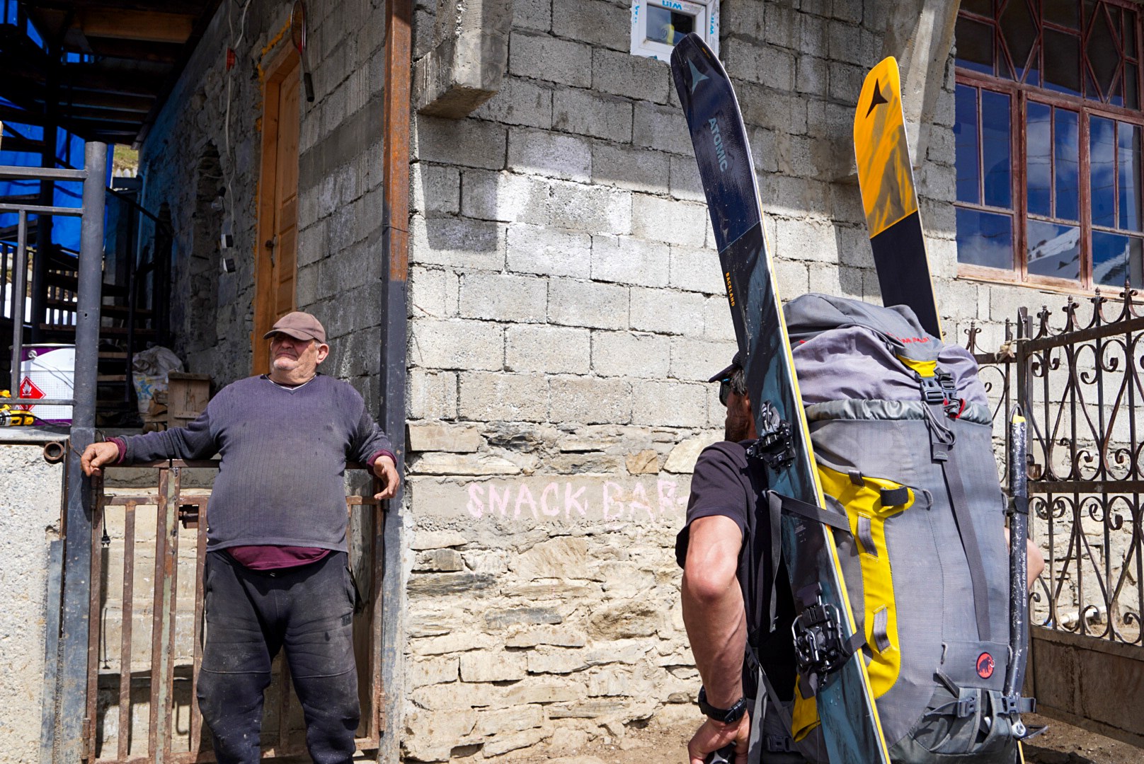 Skieurs portant leur matériel entre les maisons, secteur d’Adishi et du Tetnuldi, pendant une traversée à ski en Haute-Svanétie.
