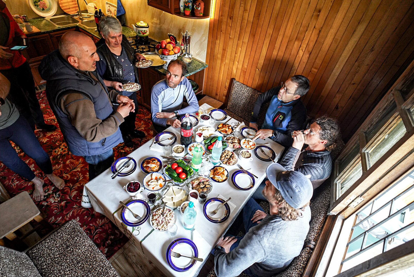 Compagnons réunis autour d’une table garnie, vallée de Becho, vers le massif de l’Ushba, pendant une traversée à ski en Haute-Svanétie.