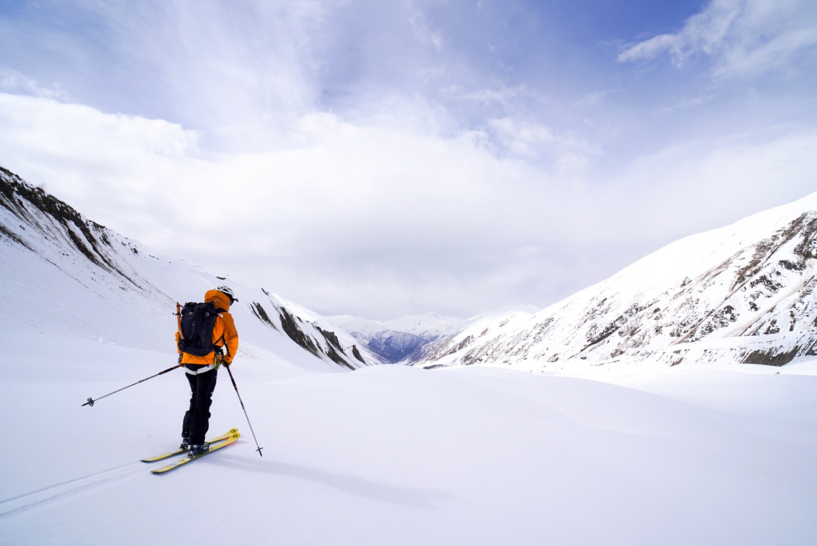 Skieur progressant skis aux pieds dans le vallon, secteur d’Ushguli et du Shkhara, pendant une traversée à ski en Haute-Svanétie.