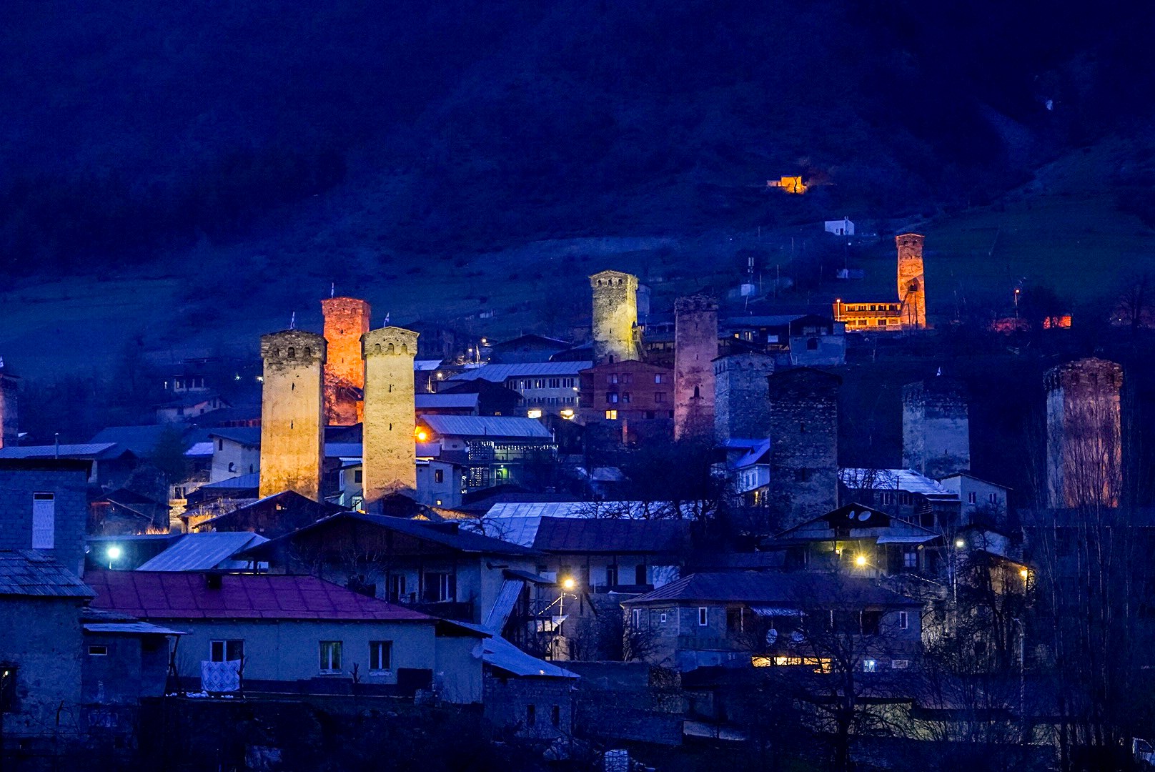 Village et tours médiévales éclairés à la nuit tombée, secteur de Mestia, pendant une traversée à ski en Haute-Svanétie.