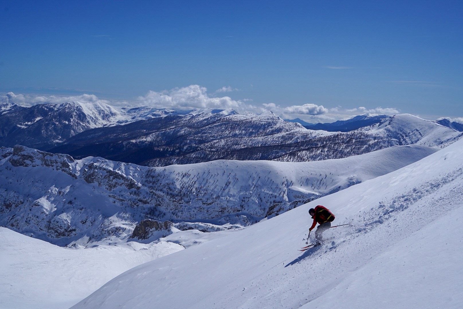Skieur traçant un virage dans une large pente enneigée, vallée de Becho, vers le massif de l’Ushba, pendant le voyage à ski en Géorgie.
