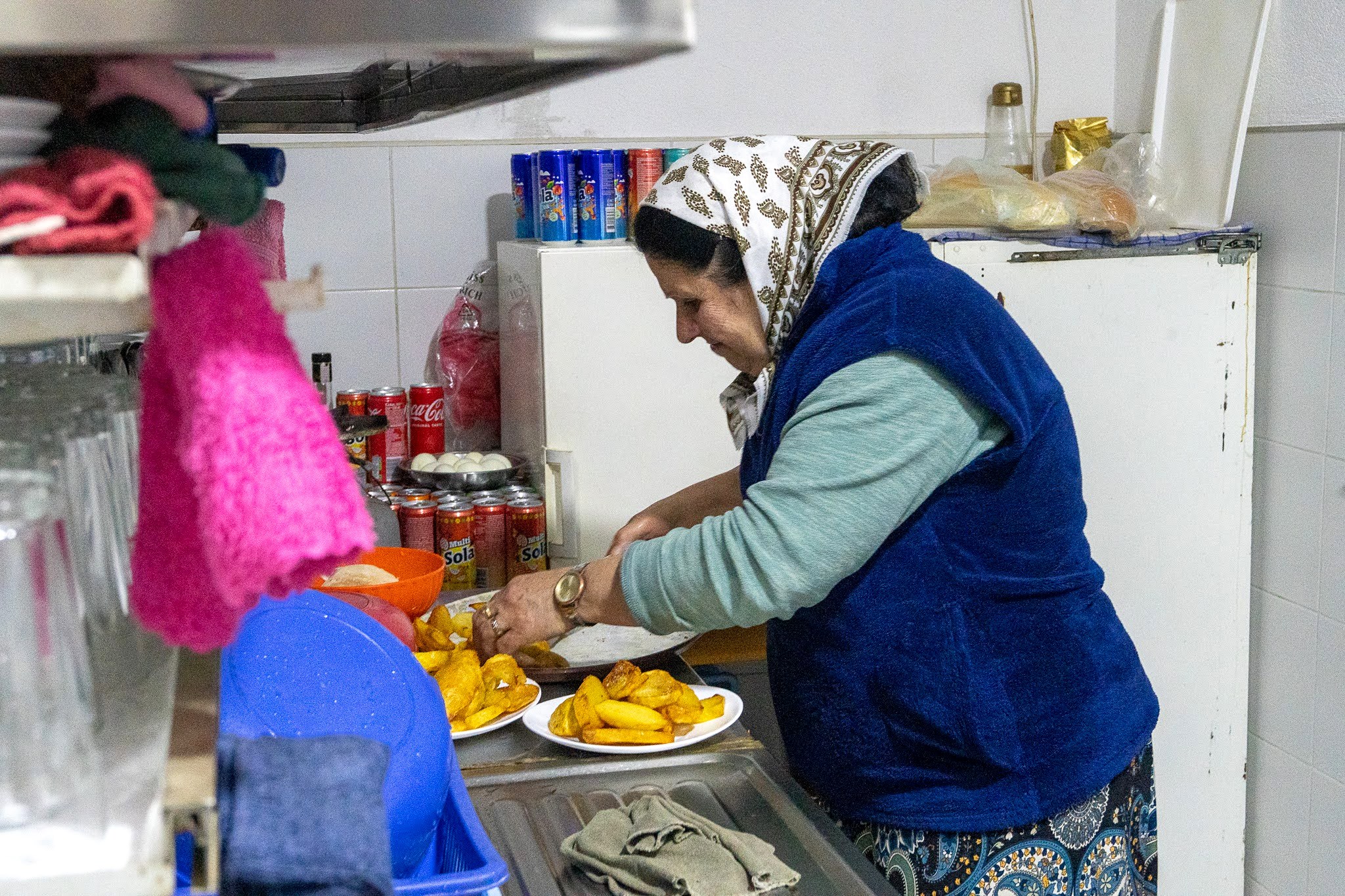 Hôtes préparant un plat dans une cuisine familiale, secteur occidental du parc national des monts Šar, pendant une traversée à ski du Kosovo.