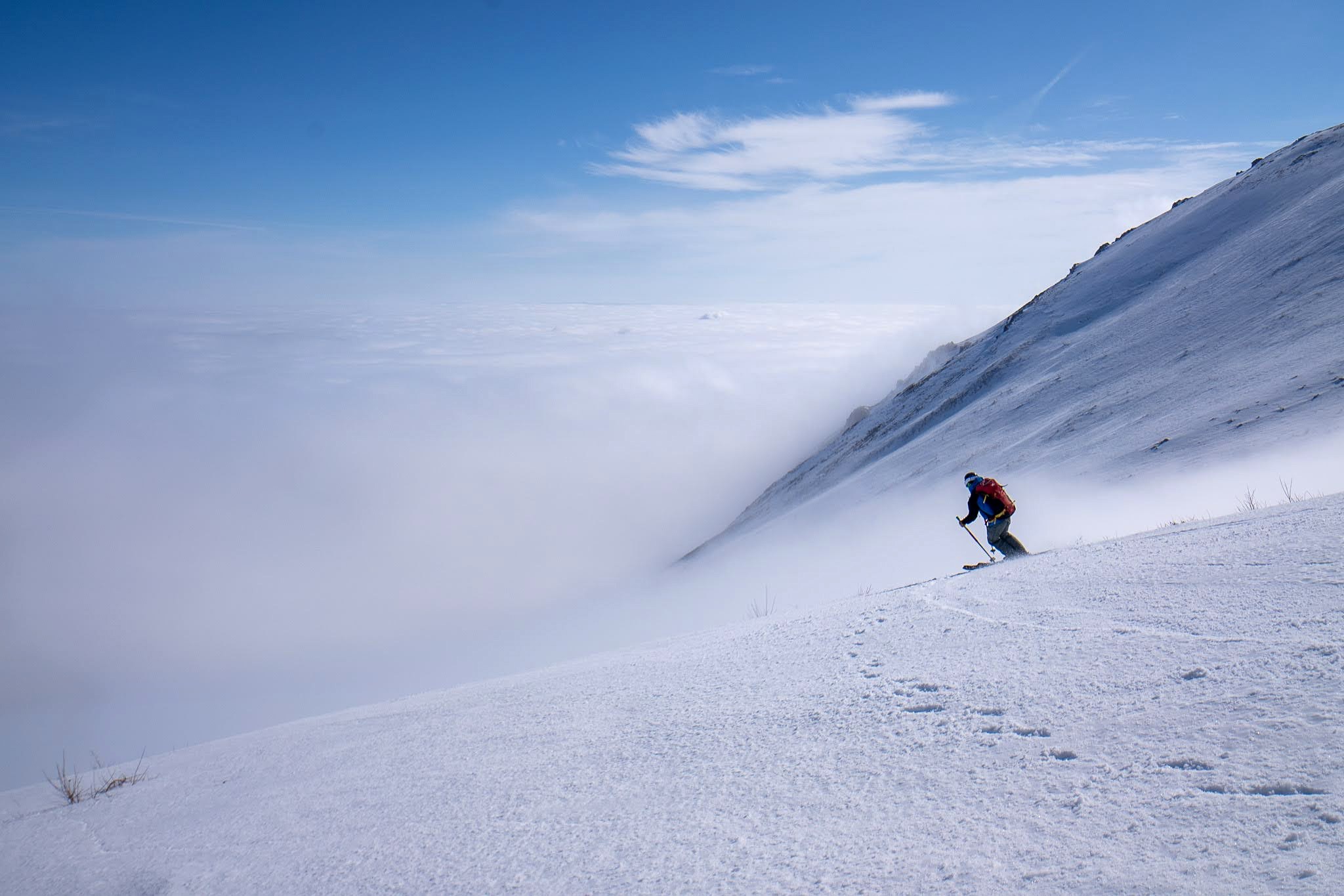 Skieur descendant une pente douce dans une ambiance bleutée, secteur oriental des monts Šar, vers le Ljuboten, pendant une traversée à ski du Kosovo.