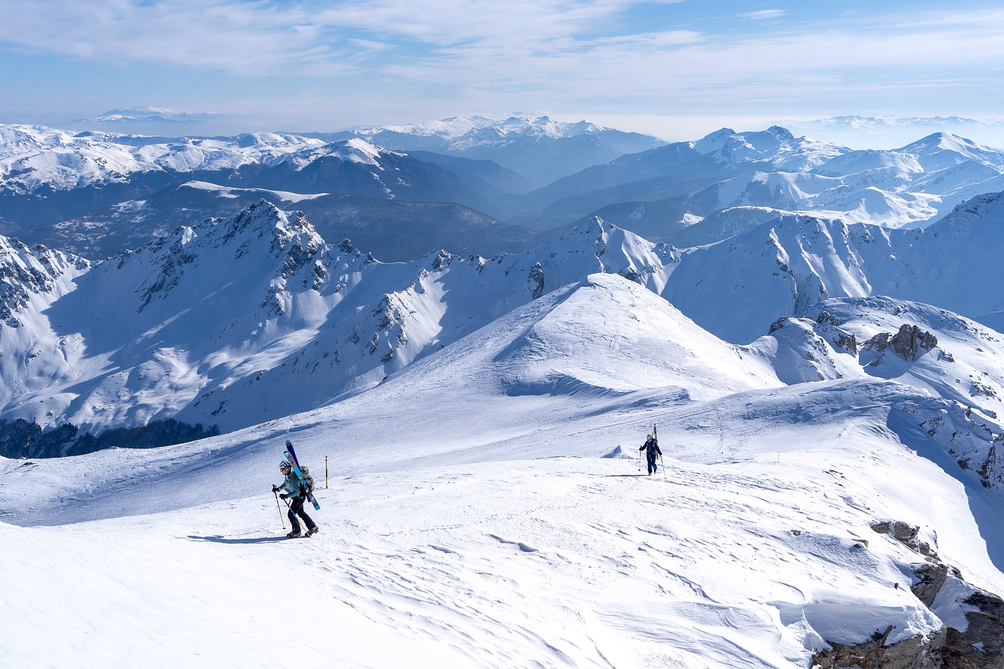 Skieur descendant une pente avec la vallée en arrière-plan, haute vallée de Brod, massif du Šar, pendant une traversée à ski du Kosovo.