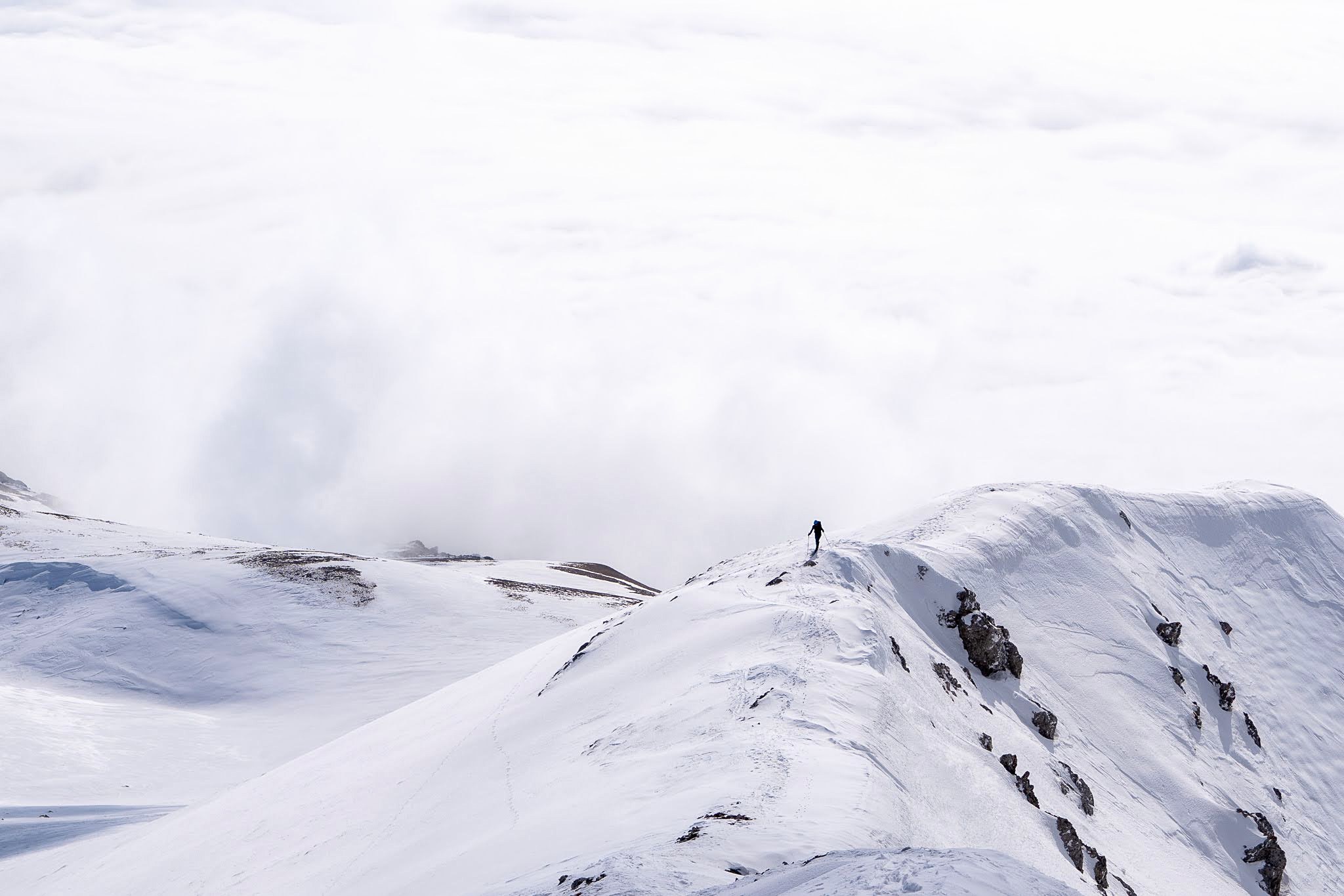 Skieurs avançant en file dans une lumière blanche, secteur oriental des monts Šar, vers le Ljuboten, pendant une traversée à ski du Kosovo.
