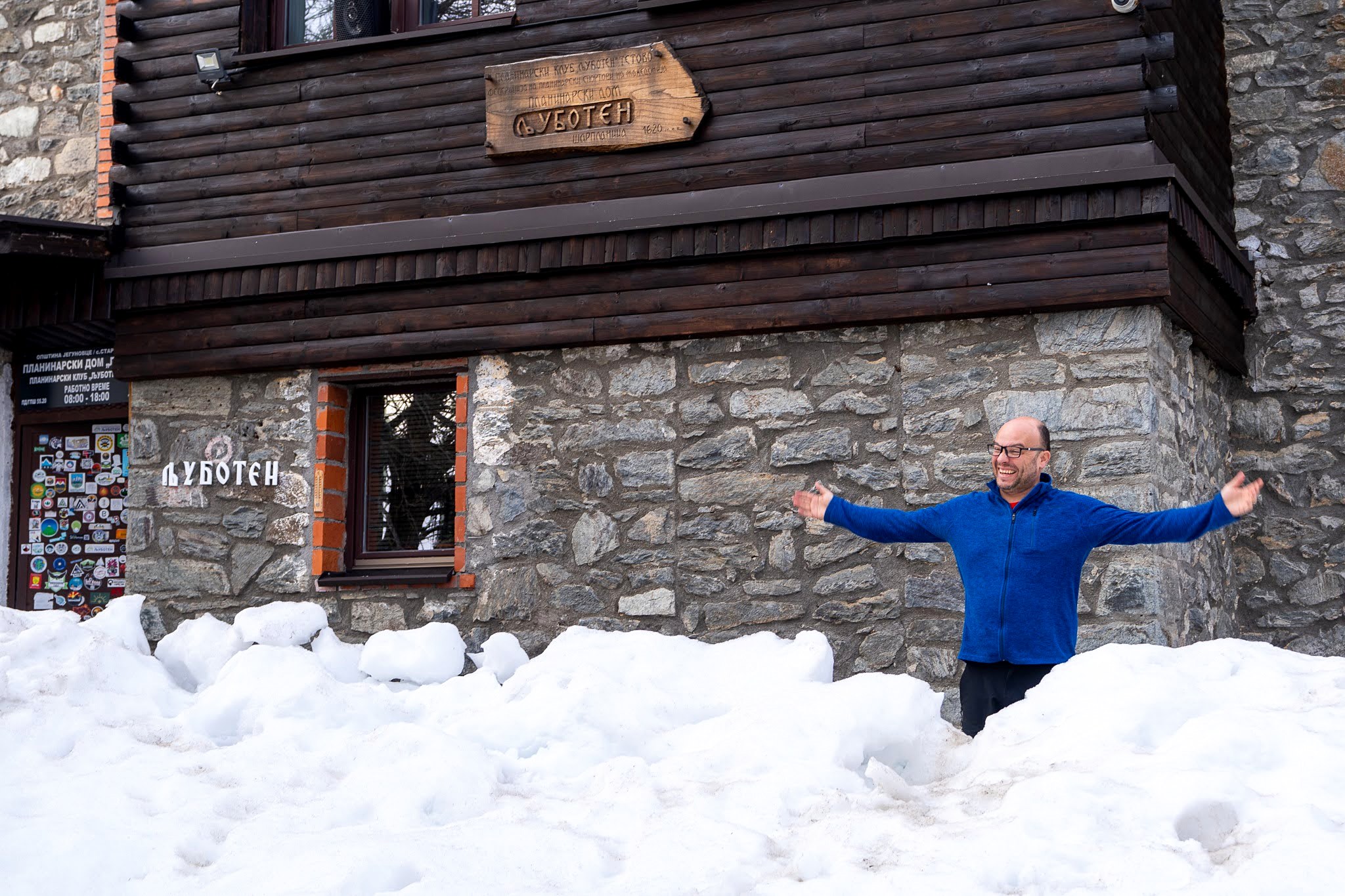 Voyageur devant une maison de pierre et de bois, secteur oriental des monts Šar, vers le Ljuboten, pendant une traversée à ski du Kosovo.