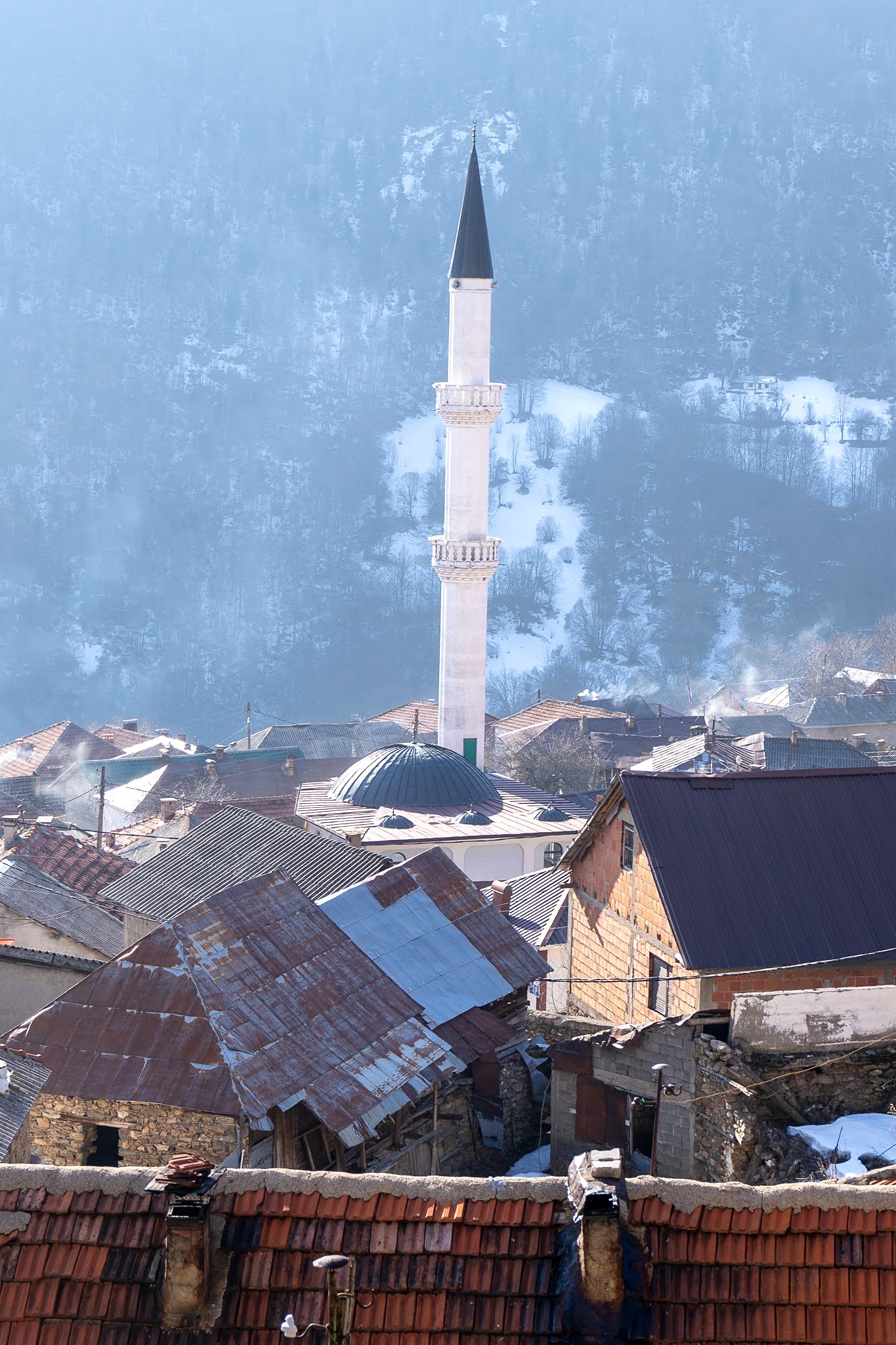 Mosquée du village cadrée à travers une fenêtre, secteur de Dragash et Brod, massif du Šar, pendant une traversée à ski du Kosovo.