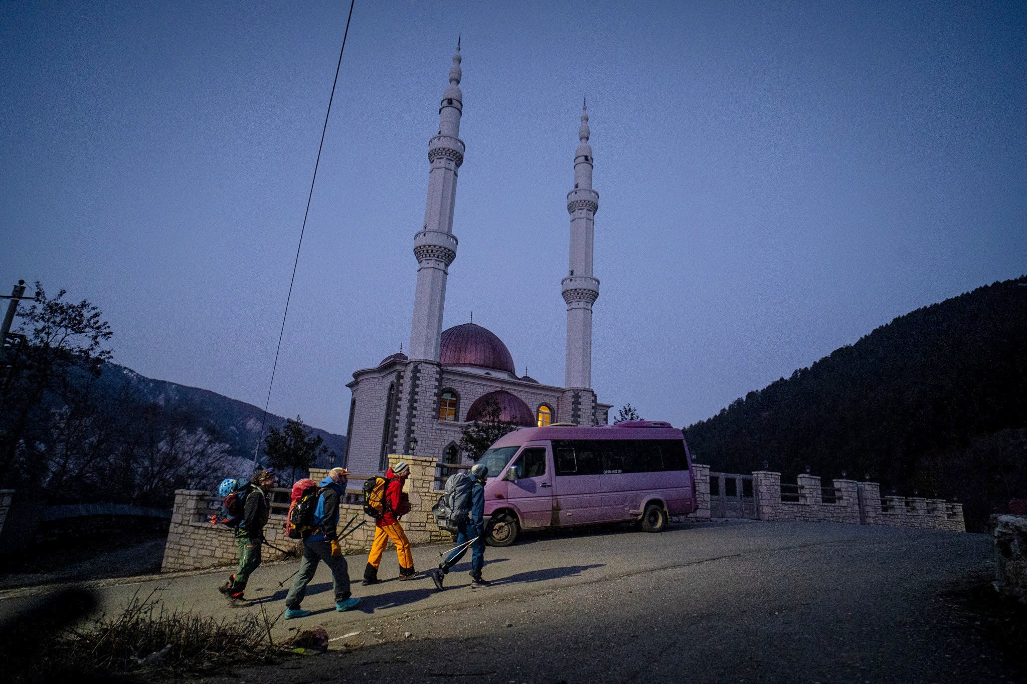Skieurs passant devant une mosquée encore éclairée, secteur occidental du massif du Šar, près du Korab, pendant une traversée à ski du Kosovo.