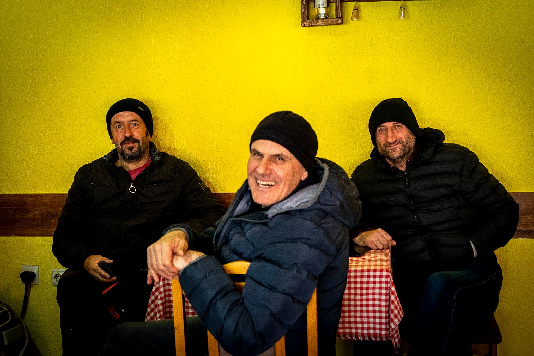 Groupe assis dans une maison du village, haute vallée de Brod, massif du Šar, pendant une traversée à ski du Kosovo.