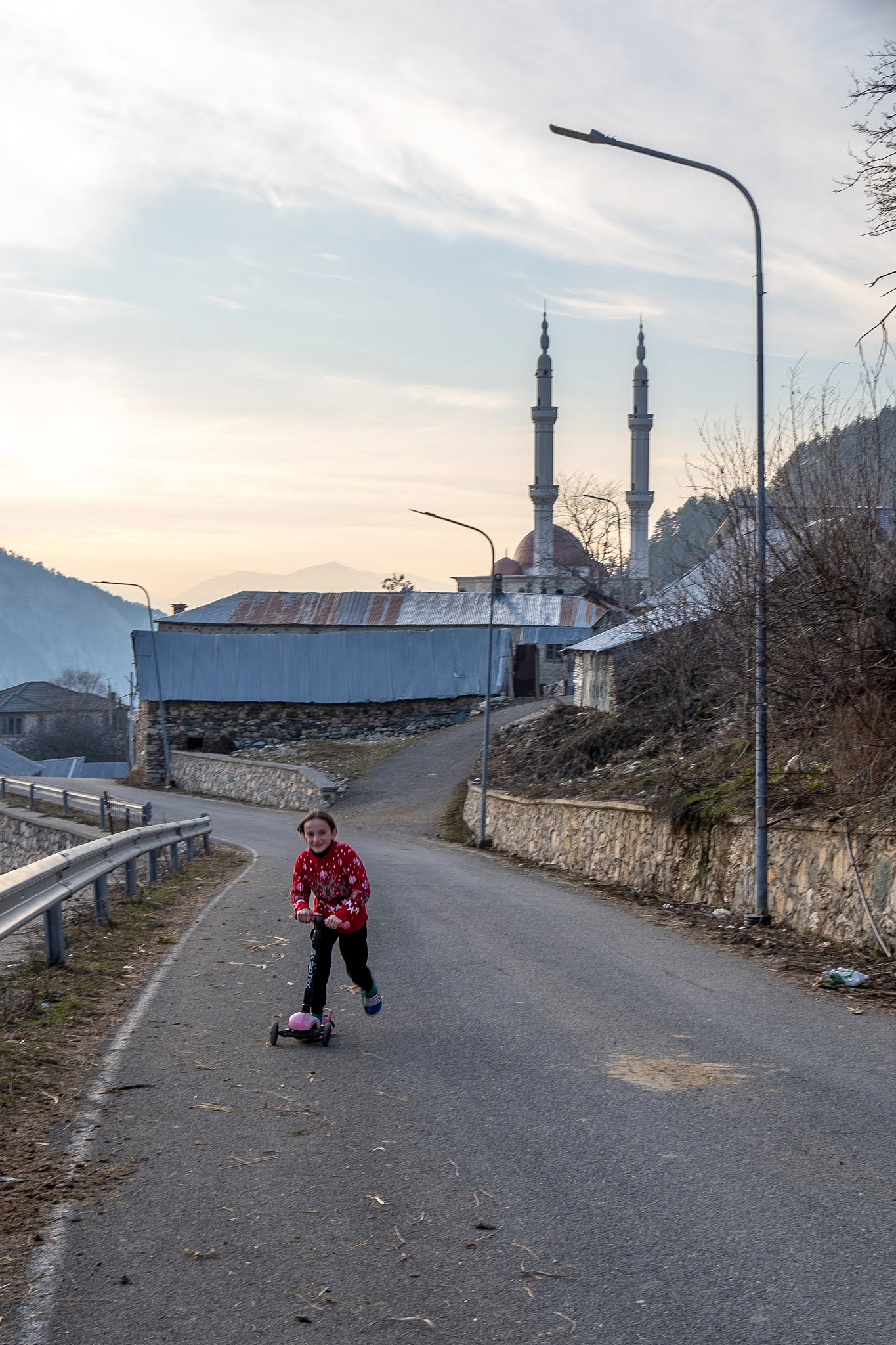 Skieur avançant dans une rue de village au crépuscule, secteur occidental du massif du Šar, près du Korab, pendant une traversée à ski du Kosovo.