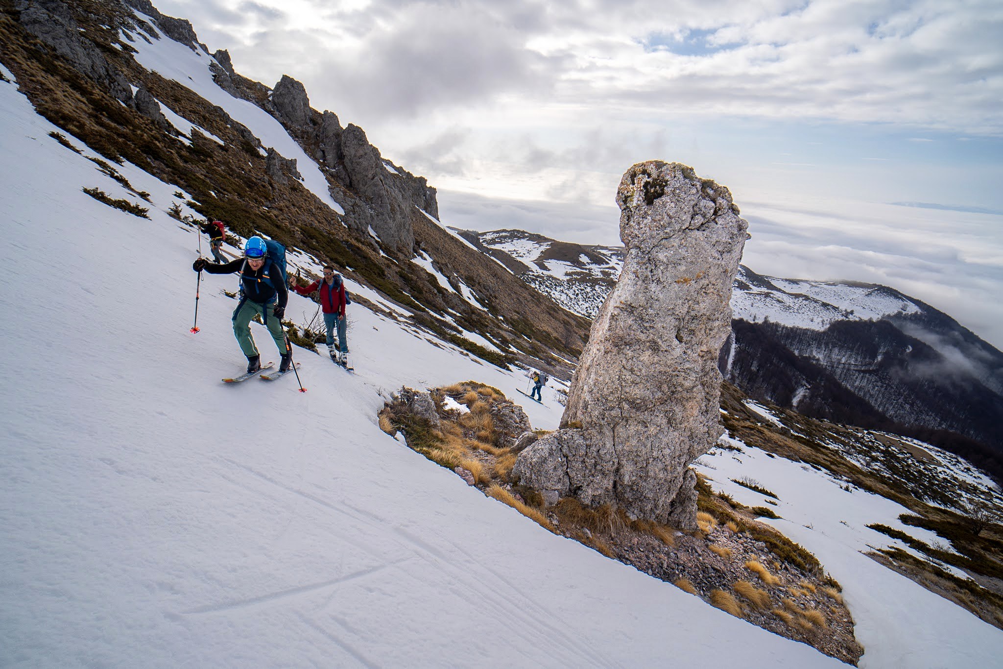 Skieur franchissant un passage entre neige et rochers, secteur oriental des monts Šar, vers le Ljuboten, pendant une traversée à ski du Kosovo.