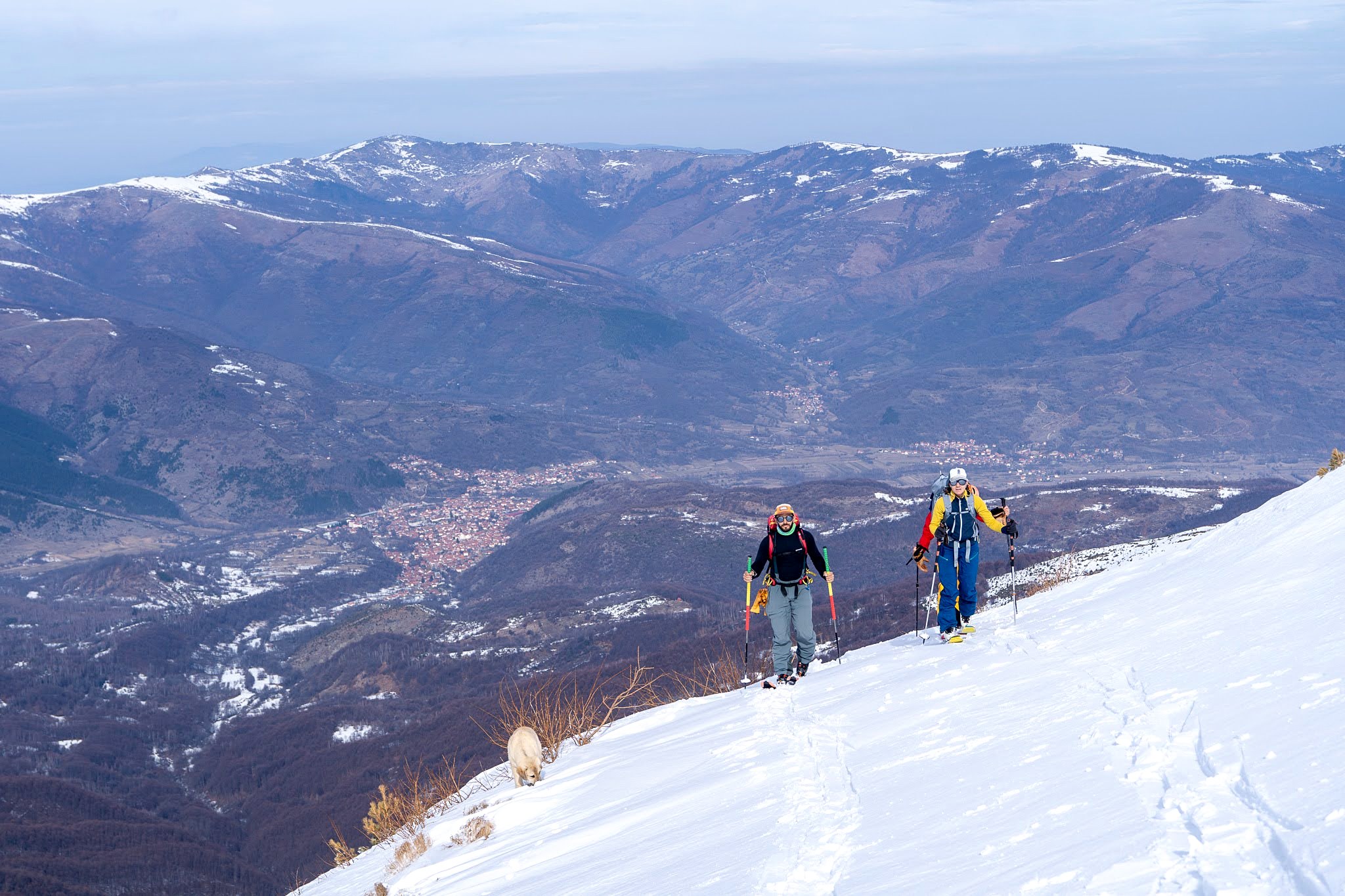 Deux skieurs traversant un versant dominant la plaine, secteur de Brezovica, monts Šar, pendant une traversée à ski du Kosovo.