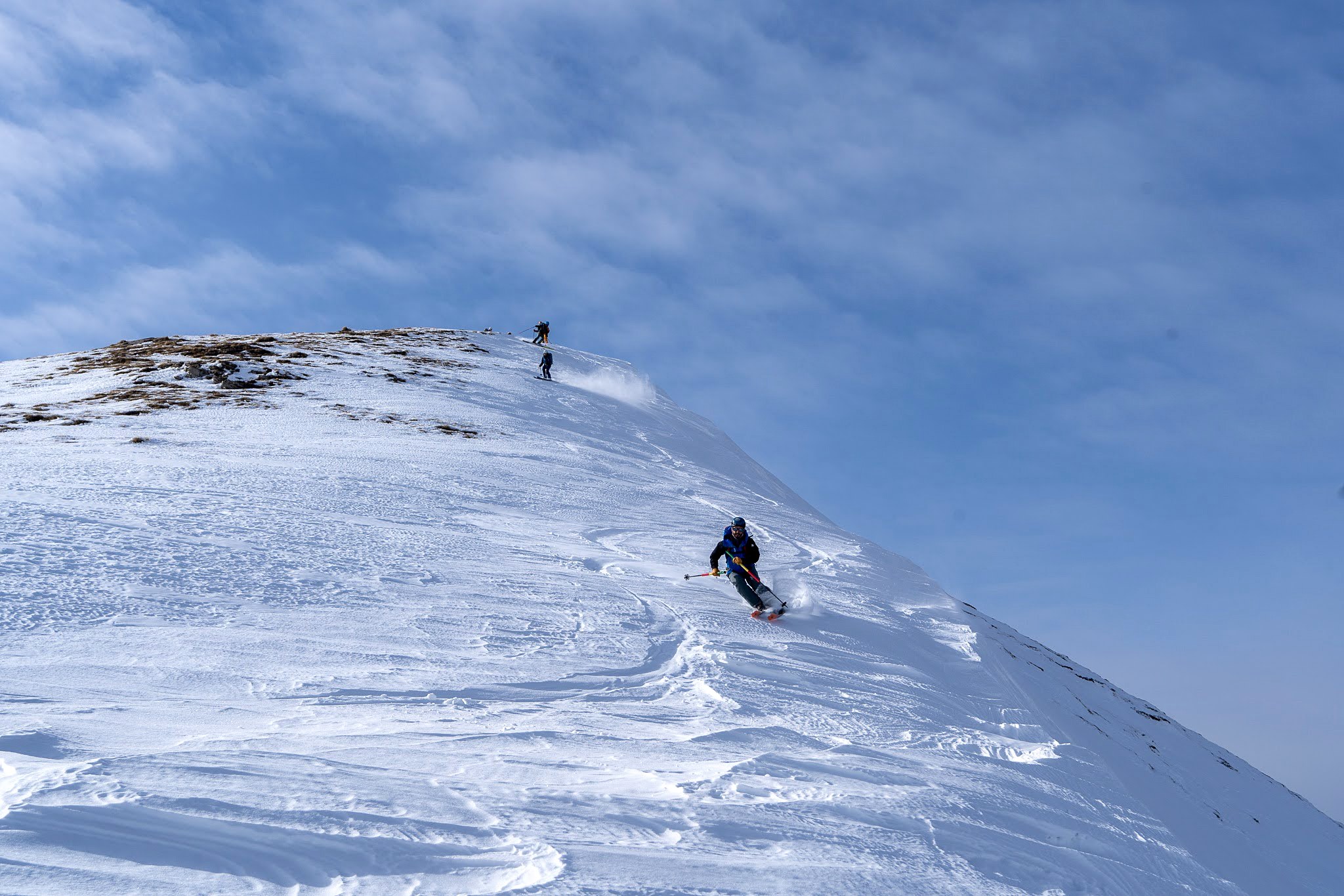 Skieur descendant un grand versant ouvert, secteur de Dragash et Brod, massif du Šar, pendant une traversée à ski du Kosovo.