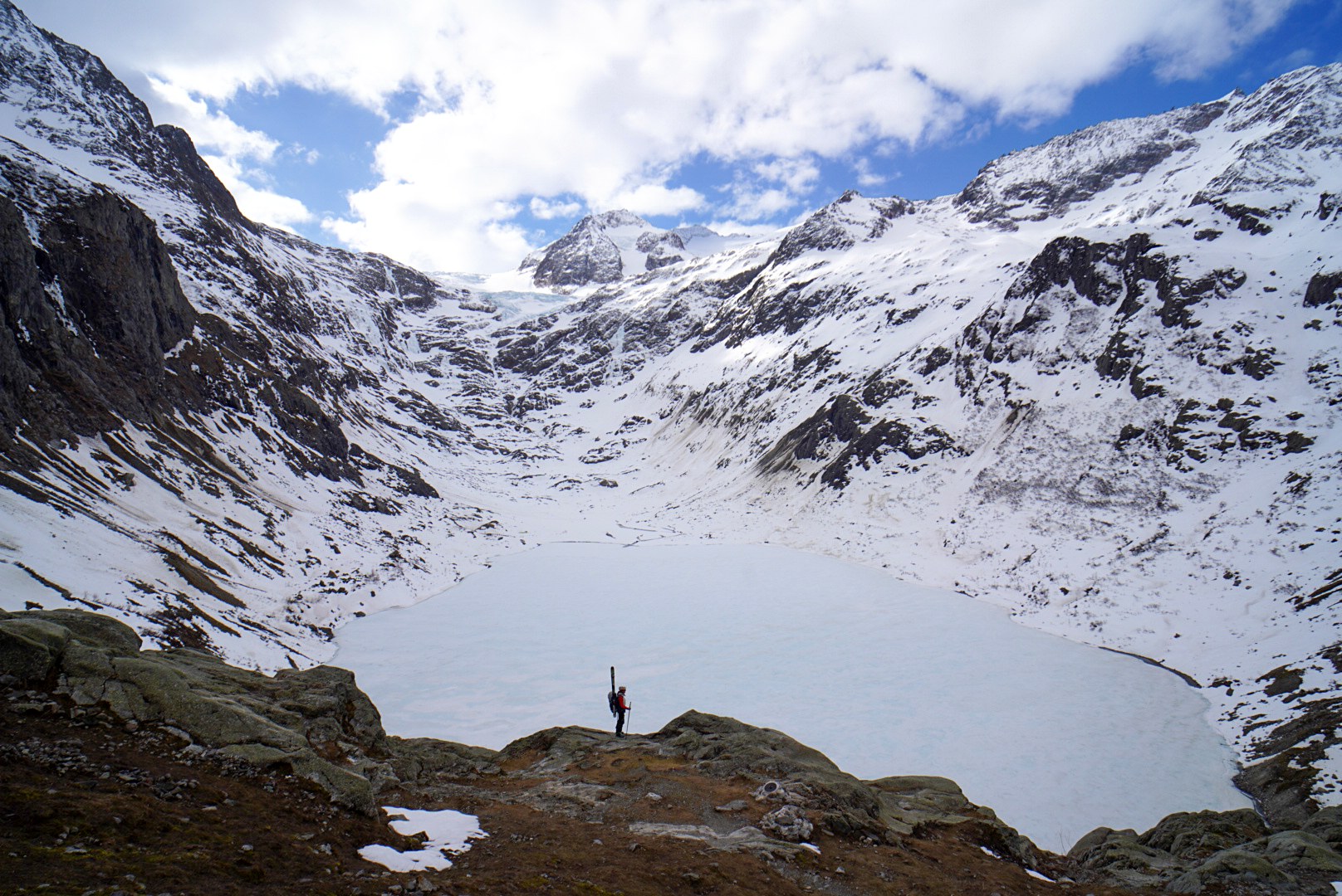 Panorama sur un lac encore gelé pendant la traversée Dammastock–Titlis dans les Alpes suisses, au jour 2 de l’itinérance.