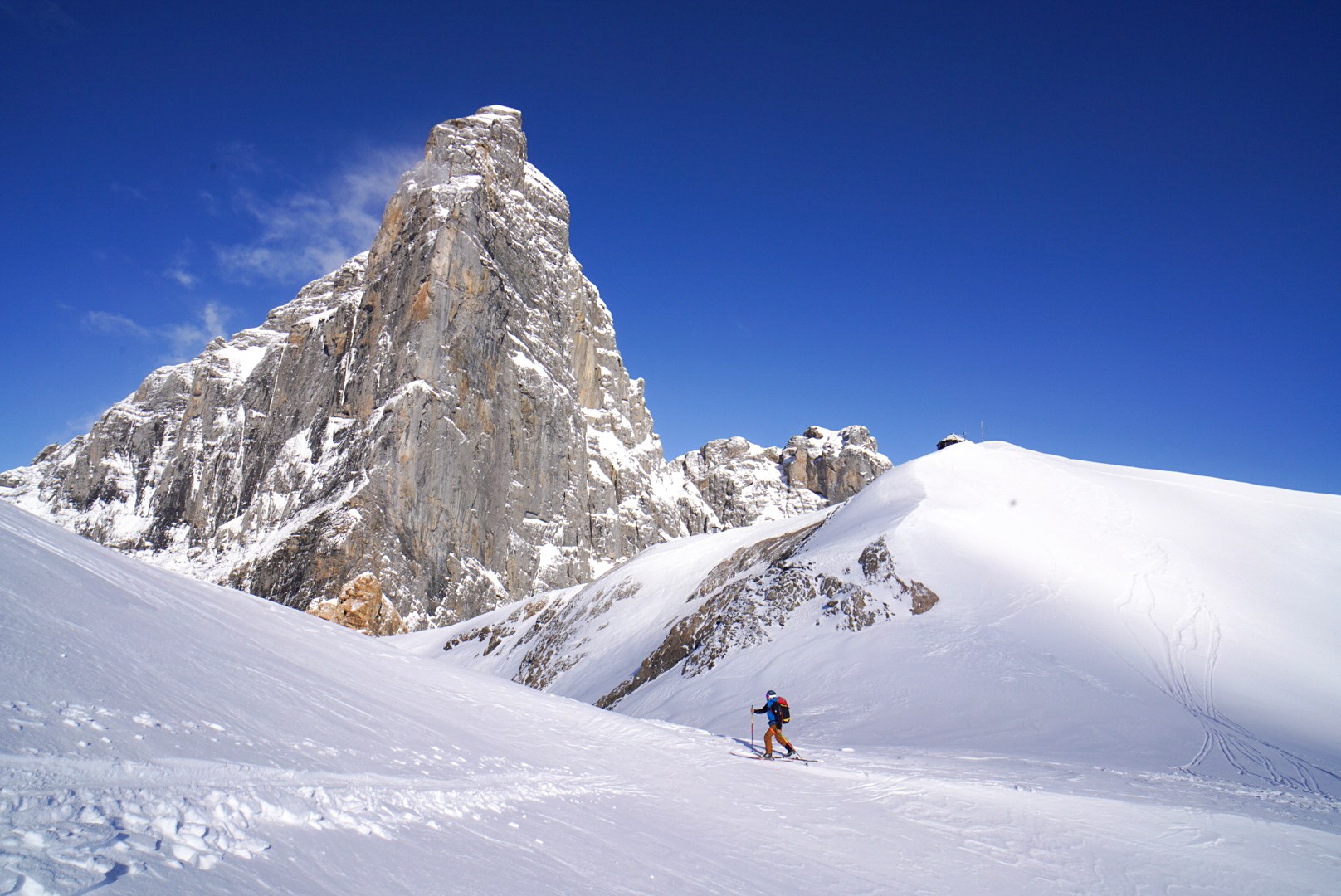 Montée à ski sous une aiguille rocheuse pendant la traversée Dammastock–Titlis dans les Alpes suisses, au jour 4 de l’itinérance.