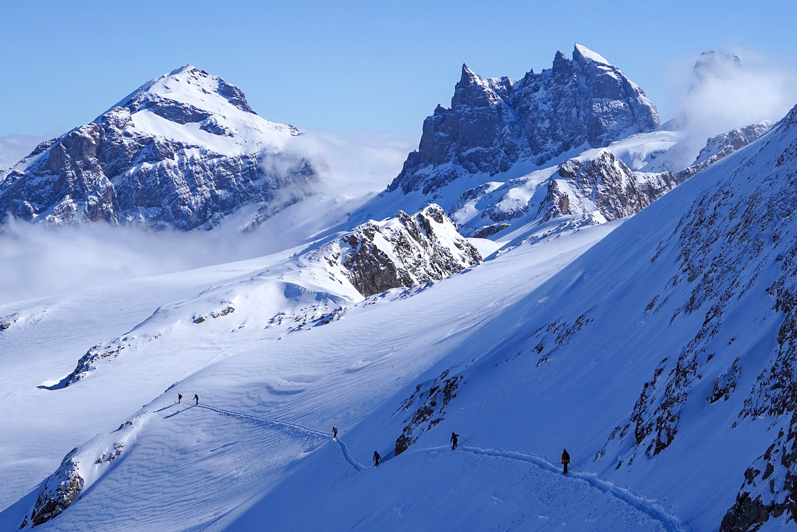 Skieurs suivant une ligne en balcon pendant la traversée Dammastock–Titlis dans les Alpes suisses, au jour 4 de l’itinérance.